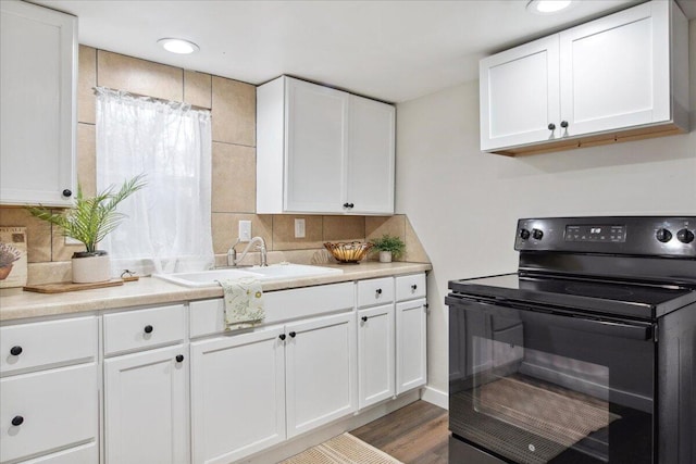 kitchen with sink, black range with electric stovetop, hardwood / wood-style floors, decorative backsplash, and white cabinets