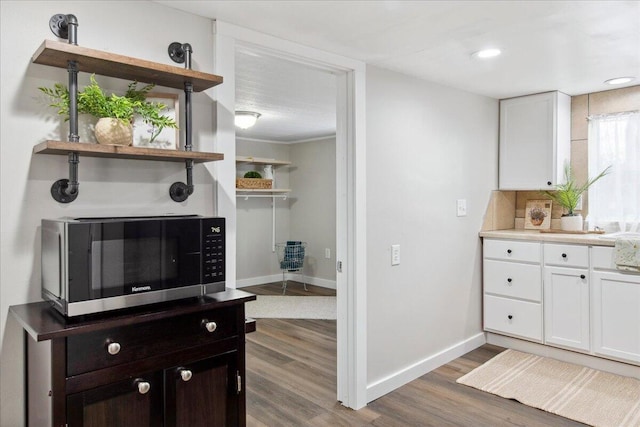 kitchen with white cabinetry, decorative backsplash, dark brown cabinets, and dark hardwood / wood-style floors