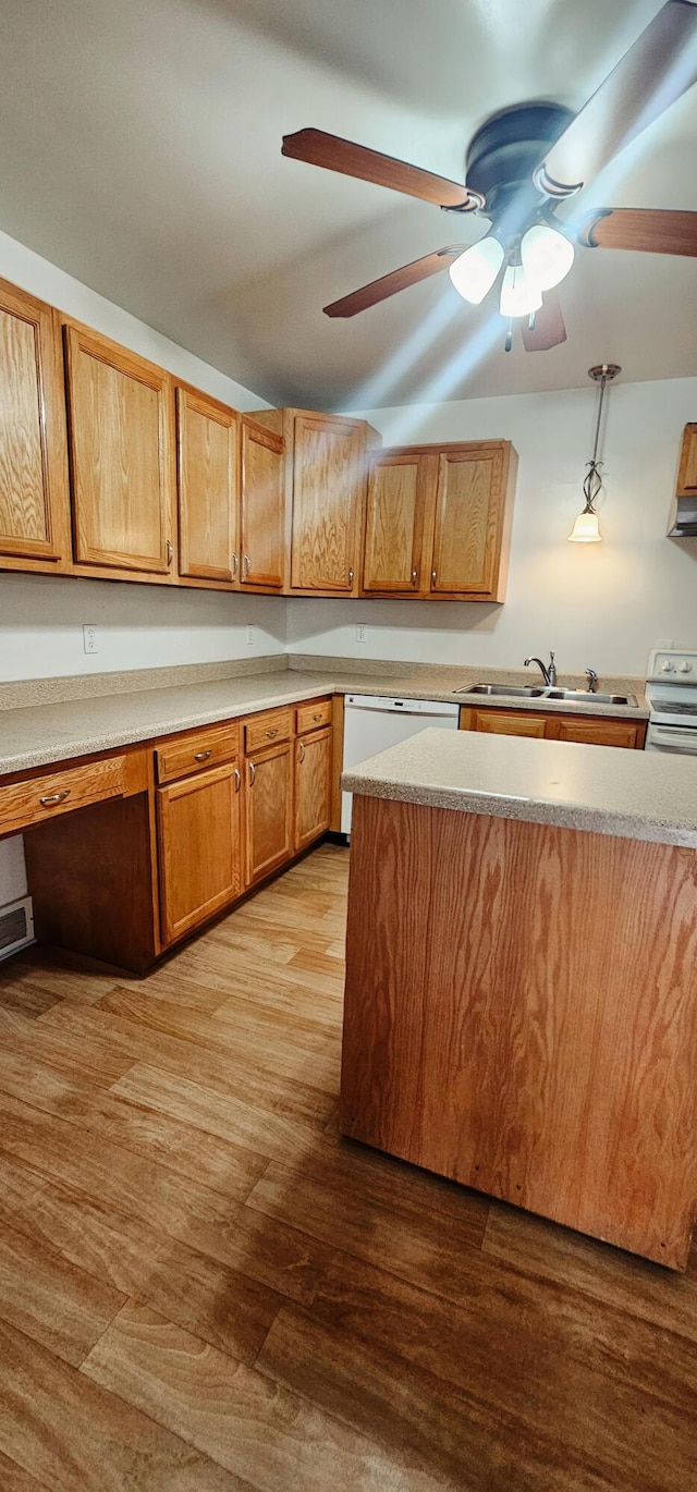 kitchen with built in desk, sink, light wood-type flooring, hanging light fixtures, and white appliances