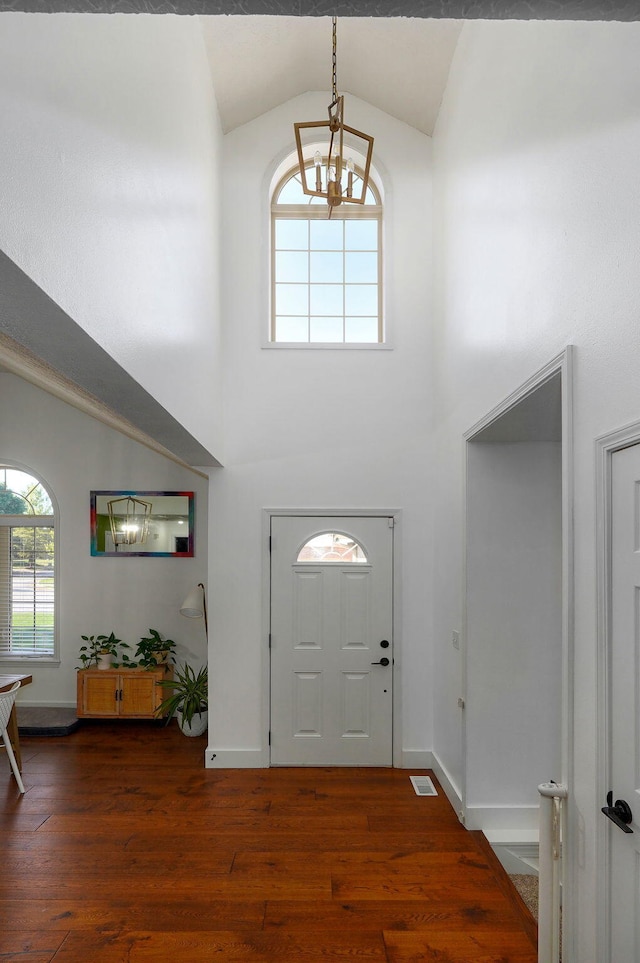 foyer entrance with an inviting chandelier, dark hardwood / wood-style flooring, and high vaulted ceiling