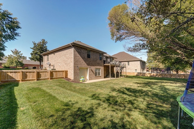 back of property featuring a trampoline, a yard, and a patio