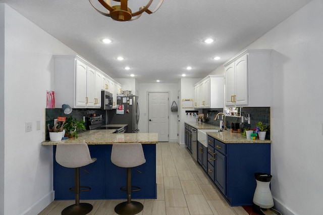 kitchen featuring stainless steel appliances, blue cabinetry, sink, and white cabinets