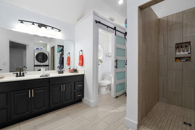 bathroom featuring vanity, stacked washer and clothes dryer, toilet, and tiled shower