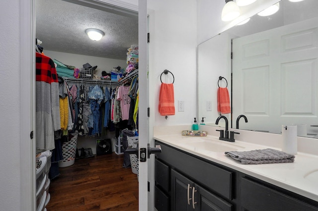 bathroom with hardwood / wood-style flooring, vanity, and a textured ceiling