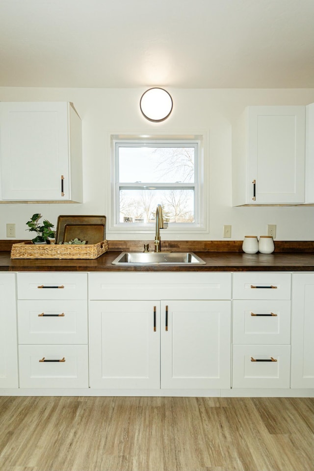 kitchen with light hardwood / wood-style floors, sink, and white cabinets