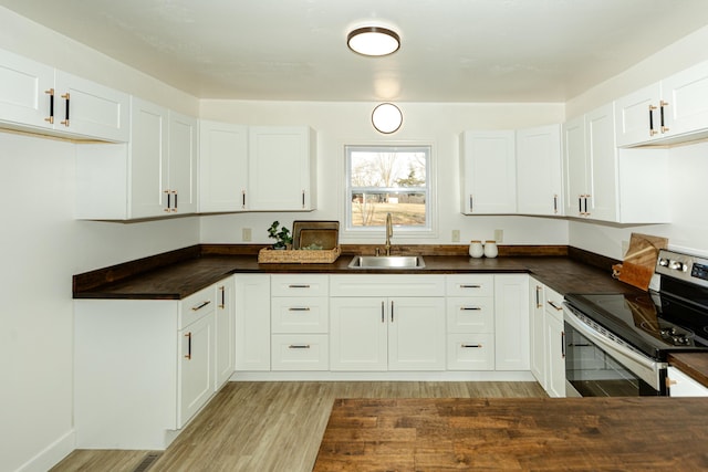 kitchen featuring stainless steel electric range oven, sink, white cabinets, and light hardwood / wood-style flooring