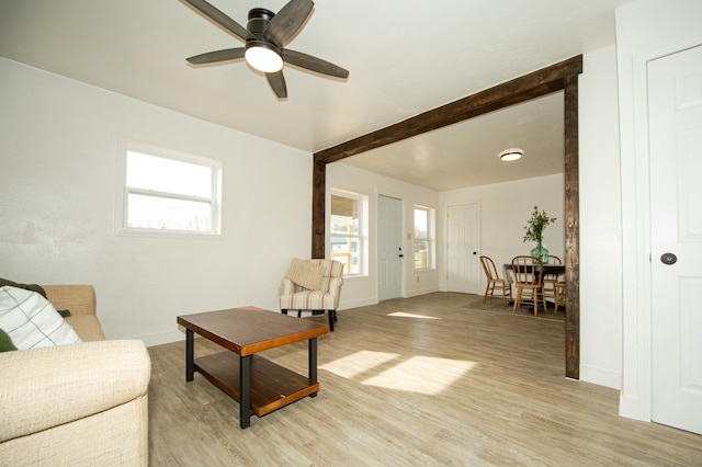 living room featuring beamed ceiling, ceiling fan, and light wood-type flooring