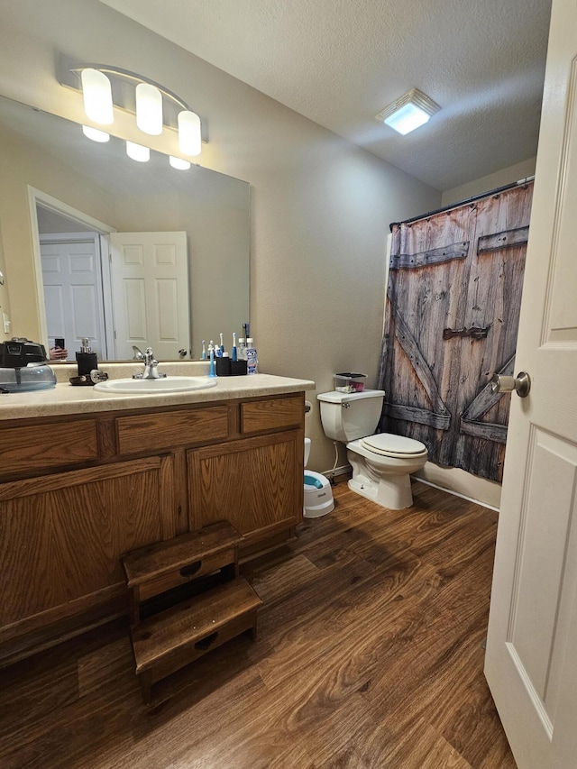 bathroom with vanity, hardwood / wood-style floors, a textured ceiling, and toilet