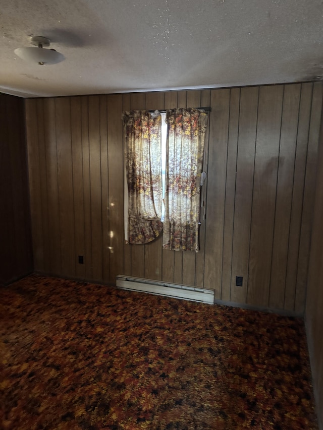 unfurnished room featuring a baseboard radiator, carpet floors, and wood walls