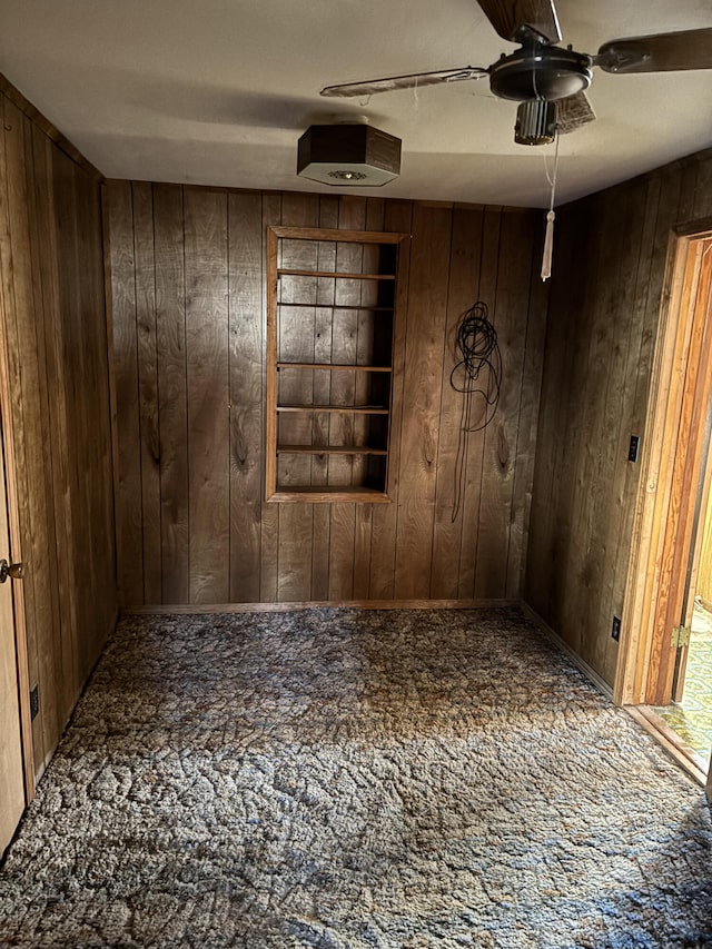 empty room featuring wooden walls and ceiling fan