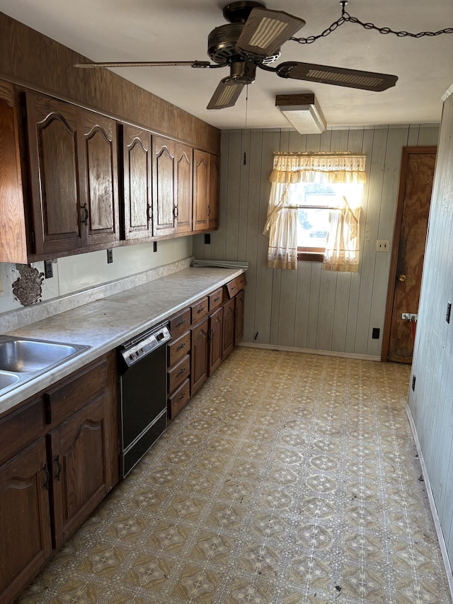 kitchen with dark brown cabinetry, ceiling fan, wooden walls, and black dishwasher