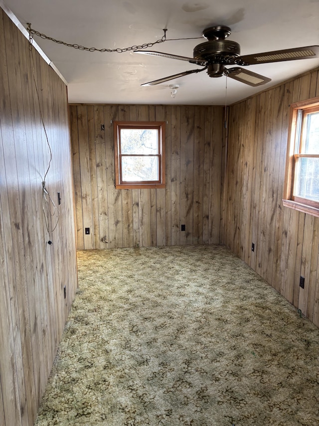 unfurnished room featuring wood walls, ceiling fan, and carpet flooring