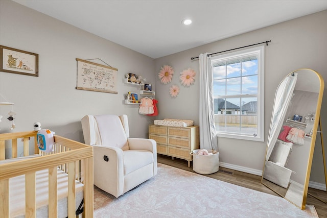 bedroom featuring a crib and light hardwood / wood-style floors