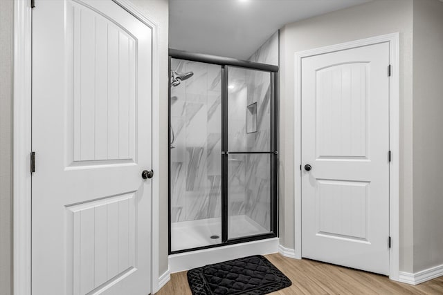 bathroom with hardwood / wood-style flooring and a shower with shower door