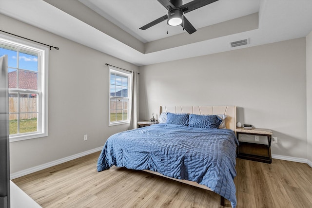 bedroom featuring ceiling fan, wood-type flooring, and a raised ceiling