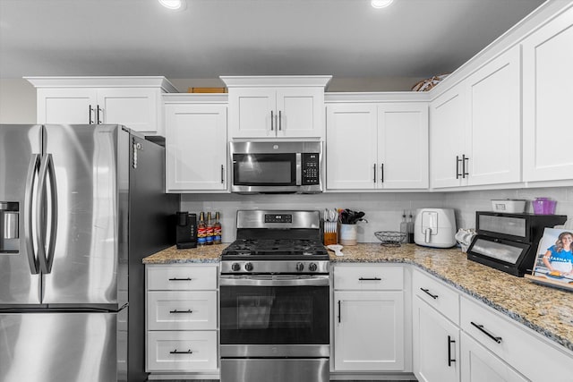 kitchen with white cabinetry, appliances with stainless steel finishes, light stone countertops, and tasteful backsplash