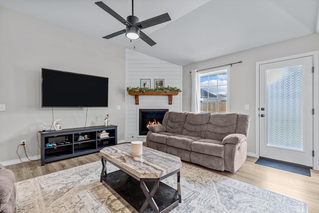 living room with a fireplace, hardwood / wood-style flooring, vaulted ceiling, and ceiling fan