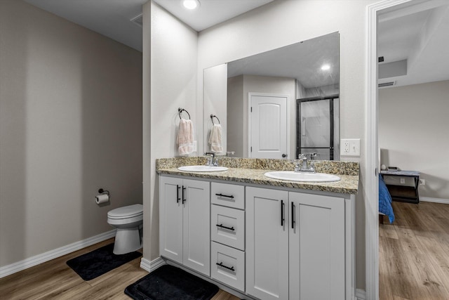 bathroom featuring hardwood / wood-style flooring, vanity, toilet, and a shower with door