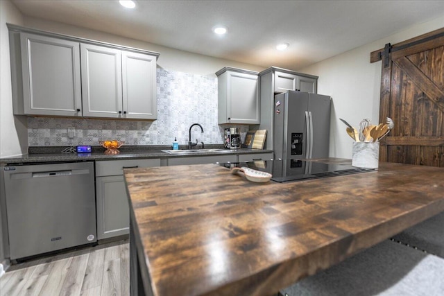 kitchen with sink, wooden counters, appliances with stainless steel finishes, gray cabinetry, and a barn door