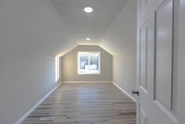 bonus room featuring vaulted ceiling, light hardwood / wood-style floors, and a textured ceiling