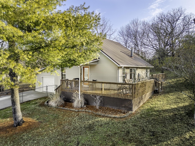 exterior space with a garage, a deck, and a lawn