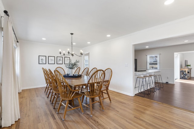 dining room featuring crown molding, a healthy amount of sunlight, an inviting chandelier, and light hardwood / wood-style floors