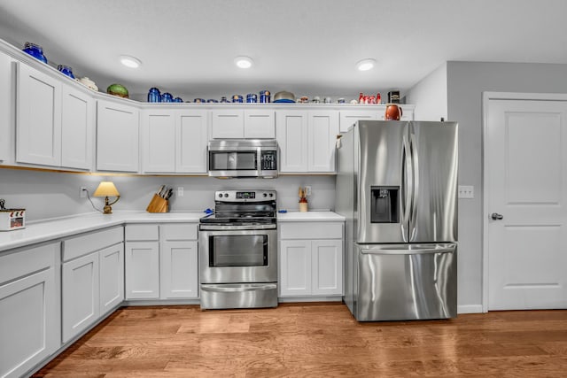 kitchen featuring stainless steel appliances, white cabinets, and light wood-type flooring