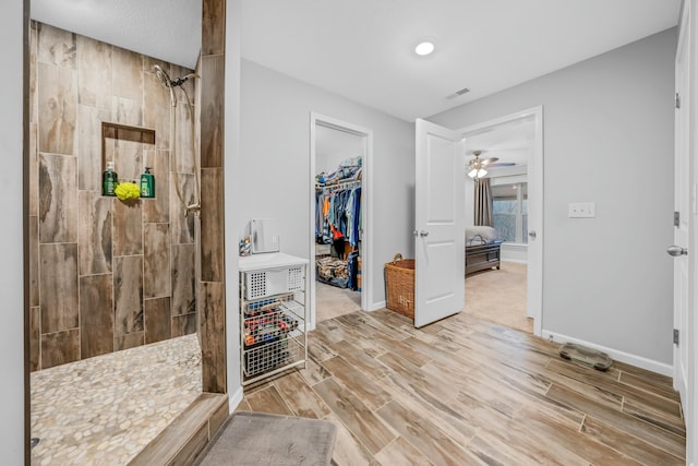 bathroom with ceiling fan and tiled shower