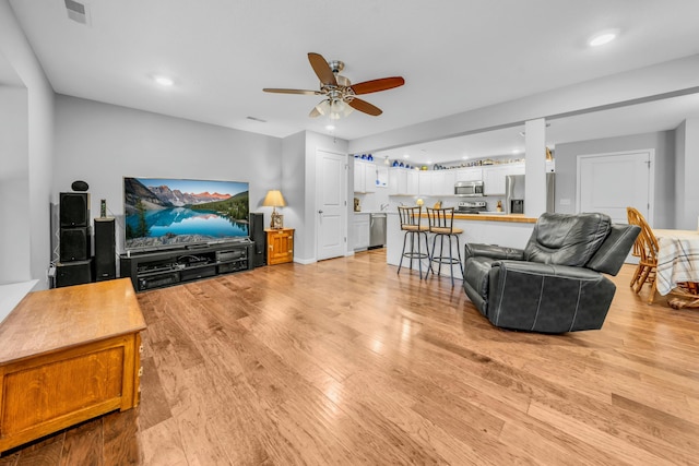 living room with ceiling fan and light wood-type flooring