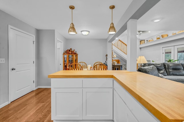 kitchen with white cabinetry, hanging light fixtures, light hardwood / wood-style flooring, and kitchen peninsula