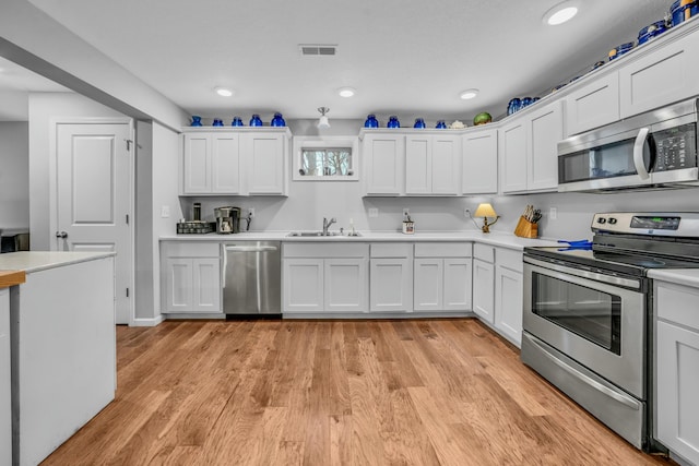 kitchen with stainless steel appliances, sink, and white cabinets