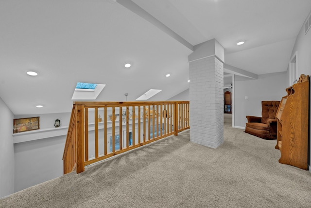 corridor with light colored carpet, lofted ceiling with skylight, and ornate columns