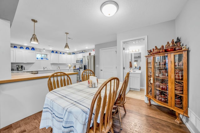 dining room featuring sink, a textured ceiling, and light hardwood / wood-style floors