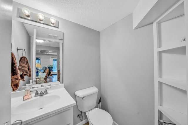 bathroom with vanity, toilet, and a textured ceiling