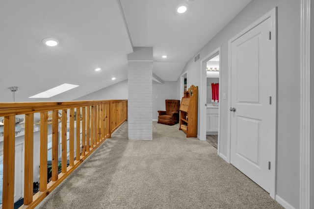 corridor featuring vaulted ceiling with skylight, carpet floors, and ornate columns