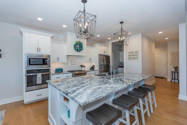 kitchen featuring hanging light fixtures, white cabinetry, appliances with stainless steel finishes, and a large island