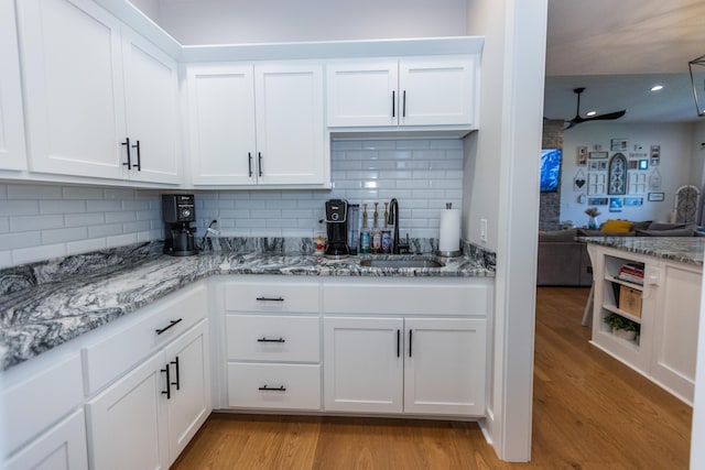 kitchen with sink, light stone counters, ceiling fan, light hardwood / wood-style floors, and white cabinets