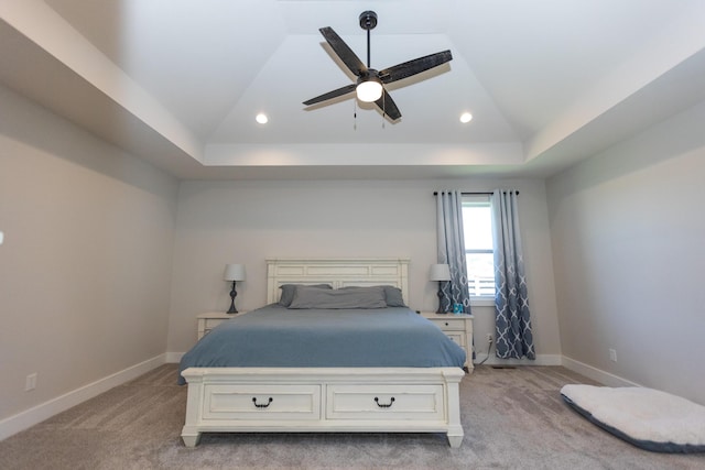 bedroom with light carpet, lofted ceiling, and a raised ceiling