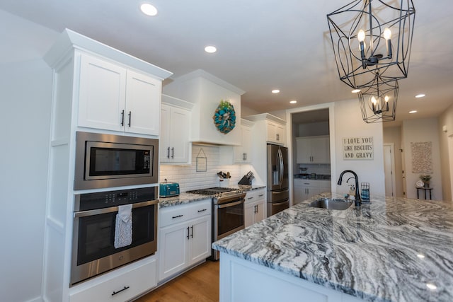 kitchen with stainless steel appliances, sink, pendant lighting, and white cabinets