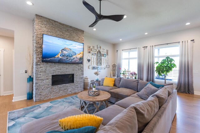 living room featuring ceiling fan, a fireplace, and light hardwood / wood-style flooring