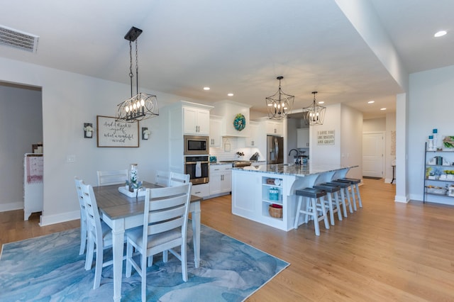 dining room featuring sink, a notable chandelier, and light wood-type flooring