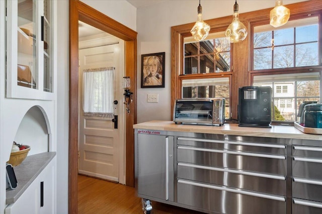 bar featuring hanging light fixtures, white cabinets, and light wood-type flooring