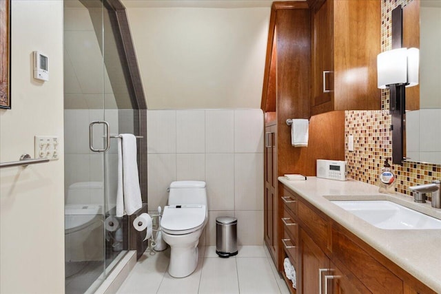 bathroom featuring toilet, a shower with shower door, tile walls, vanity, and tile patterned flooring