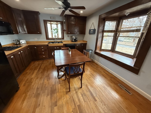 kitchen featuring sink, light hardwood / wood-style flooring, ceiling fan, butcher block counters, and black appliances