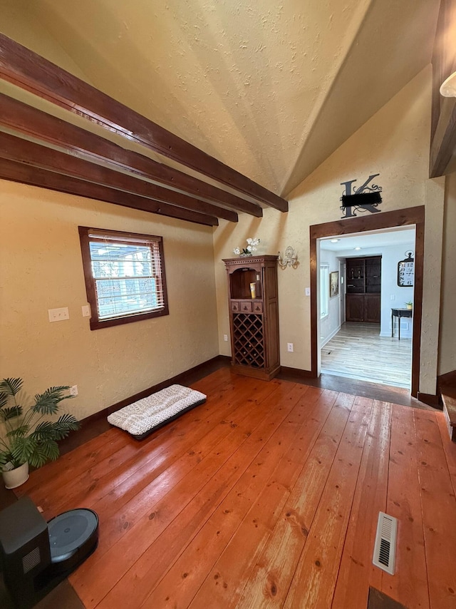 unfurnished living room featuring lofted ceiling with beams and hardwood / wood-style floors