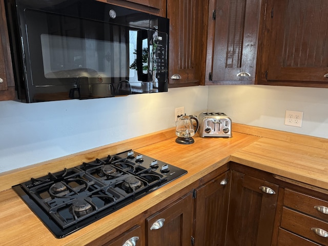 kitchen featuring dark brown cabinets, black appliances, and wooden counters