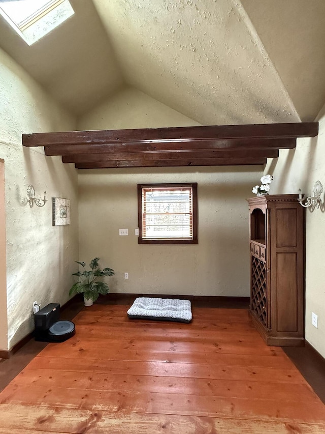 additional living space featuring lofted ceiling with skylight and hardwood / wood-style floors