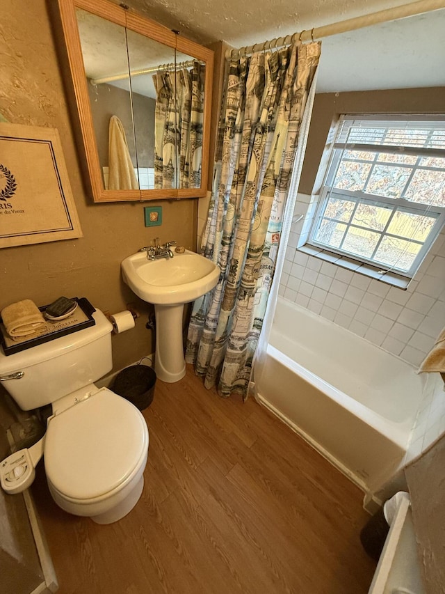 full bathroom with hardwood / wood-style flooring, shower / tub combo with curtain, toilet, and sink