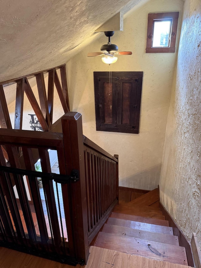 stairs featuring lofted ceiling, wood-type flooring, and a textured ceiling