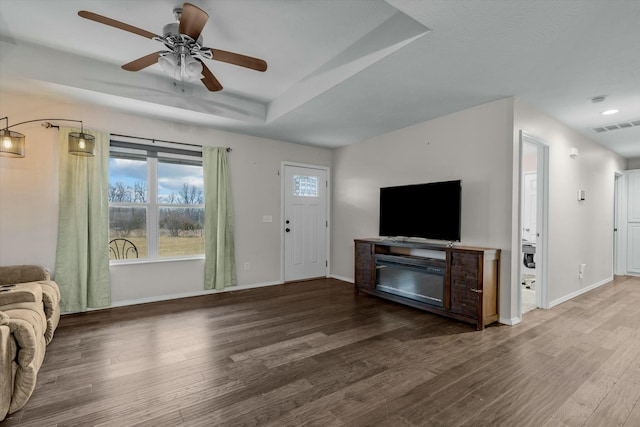 unfurnished living room with ceiling fan, wood-type flooring, and a raised ceiling